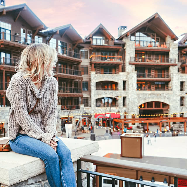 A woman sitting on a bench looking back at The Ranahan by Welks Resorts in Breckenridge, CO