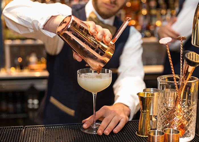 A bartender at a speakeasy pours a drink